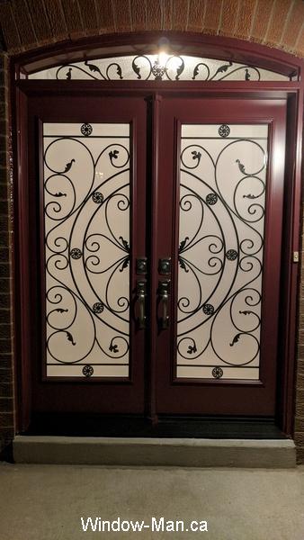 Double front entry door with curved transom. Rochester wrought iron glass inserts. Burgundy color